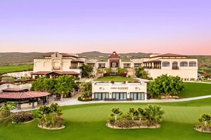 Eine Golfakademie mit mehreren Gebäuden, einem gepflegten Rasen und blauem Himmel.