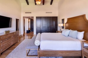 Ein geräumiges Schlafzimmer mit einem großen Bett, einem Holz-Kopfteil und einem flachbildfernseher an der Wand.