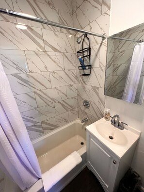 Ein Badezimmer mit Badewanne, Waschbecken, Spiegel und Duschvorhang.