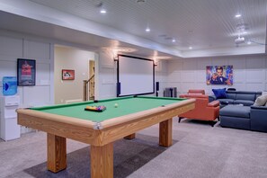 A pool table with a green felt surface, a white projection screen, and a blue water dispenser.