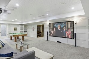 Een ruimte voor ontspanning met een pooltafel, een zithoek en een grote flatscreen televisie aan de muur.