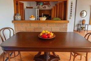 A dining table with a fruit bowl in the center, surrounded by chairs.