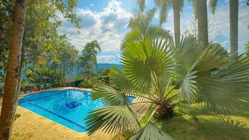 Una piscina circondata da palme e vegetazione.
