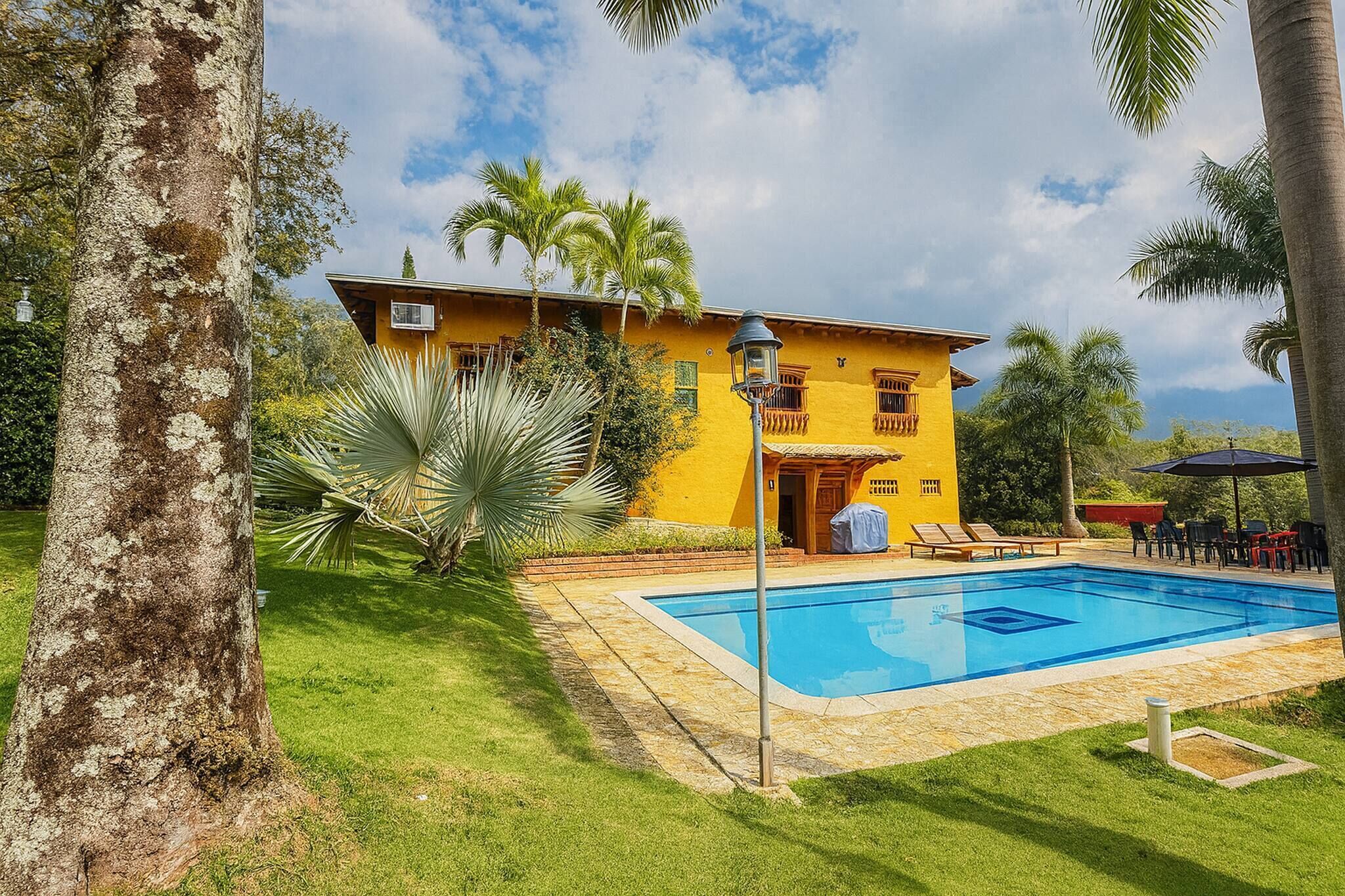 Un bâtiment jaune doté d’une piscine, entouré de palmiers et d’une pelouse bien entretenue.