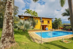 A yellow building with a swimming pool, surrounded by palm trees and a well-maintained lawn. - Paraíso Las Palmeras With Pool in San Jerónimo (San Jerónimo)