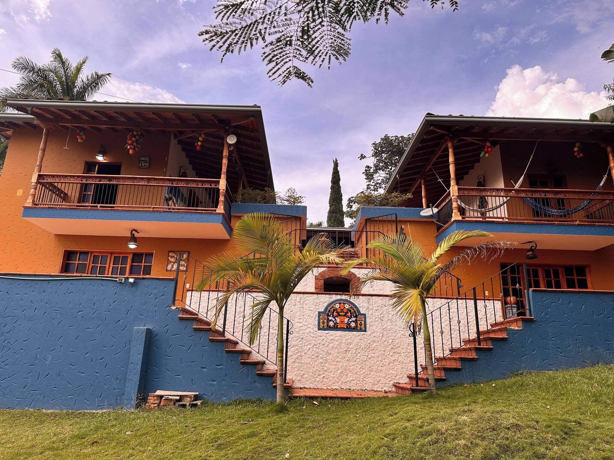 Um edifício simétrico com duas varandas, uma entrada central e um emblema decorativo.