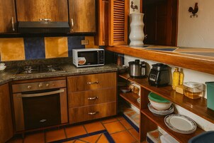 Una cocina con armarios de madera, microondas, estufa y cafetera.