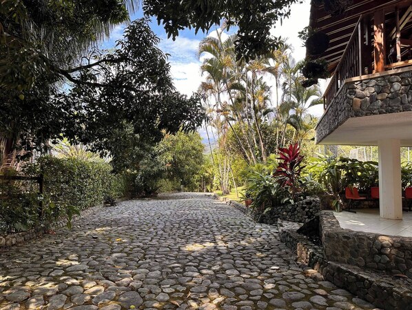 A stone pathway leading to a building with a stone facade and a balcony.
