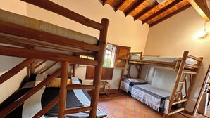 A rustic room with wooden bunk beds, a sofa, and a chair.