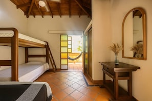Una habitación con literas, un escritorio, un espejo y vistas a un espacio exterior con una hamaca.
