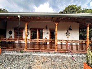 A traditional house with a stone-paved courtyard, wooden columns, and a decorative railing.
