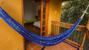 Una hamaca en un balcón con vista a una habitación que tiene una cama y una ventana.