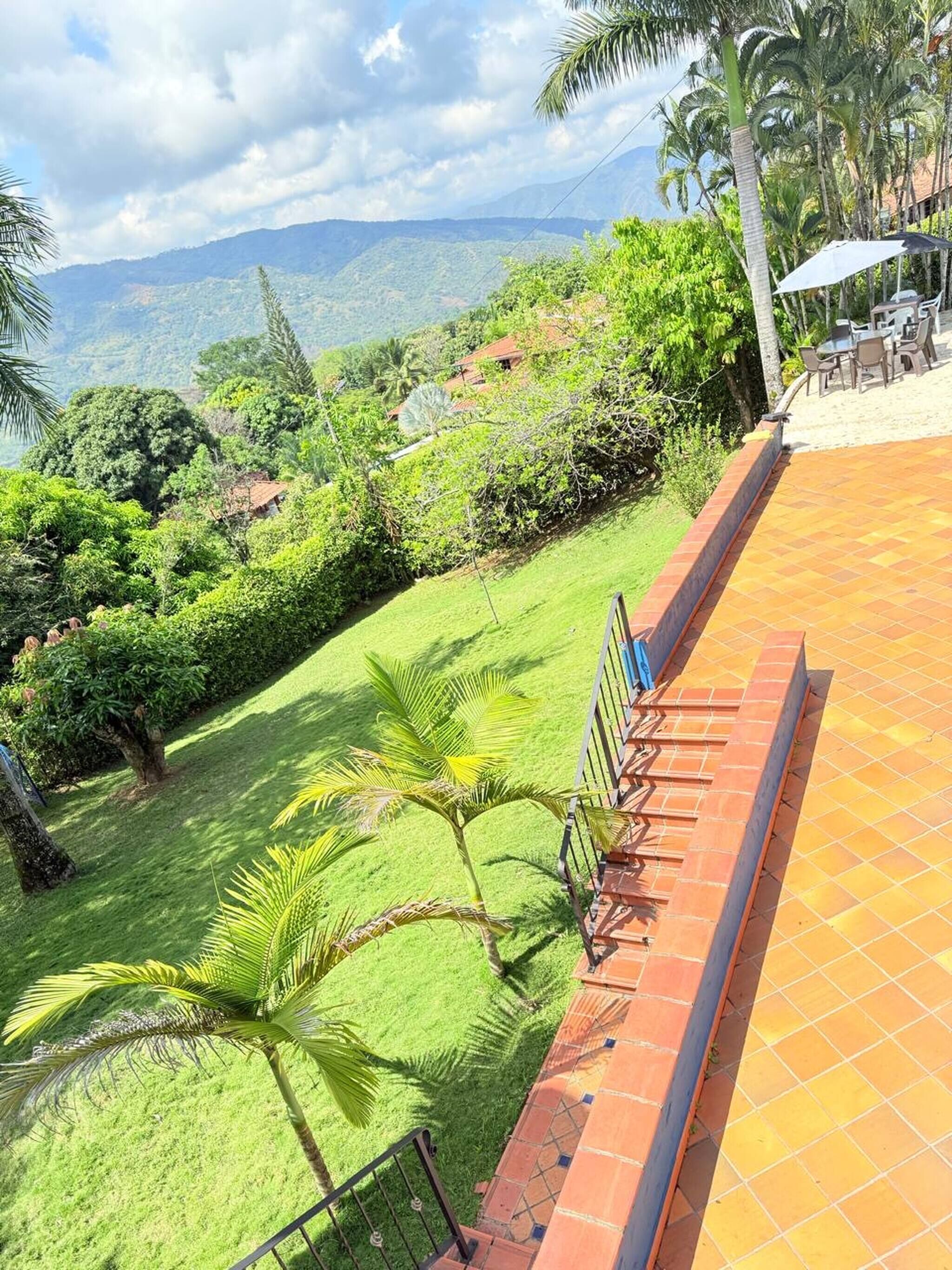Una terraza con vistas a un paisaje exuberante, que incluye árboles y colinas lejanas.