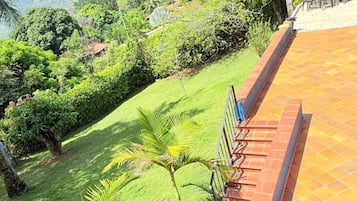 Una terraza con vistas a un paisaje exuberante, que incluye árboles y colinas lejanas.