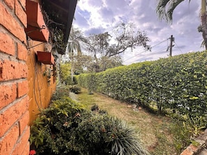 Un jardín con muro de ladrillo, diversas plantas y un seto.