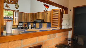 A kitchen with wooden cabinets, a tiled backsplash, and a hanging light fixture.
