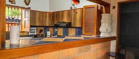 A kitchen with wooden cabinets, a tiled backsplash, and a hanging light fixture.