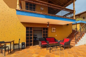 A two-story building with a balcony, outdoor seating area, and a staircase.