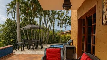 Un patio al aire libre con mobiliario de mimbre, una piscina y vistas a palmeras.