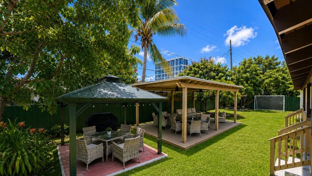 Eine Terrasse mit Gartenmöbeln, einem überdachten Sitzbereich und einem Gebäude mit Gründach.