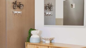 A wooden cabinet with a mirror above it, a small plant, and a white bowl on top. - Chic Noosa Pad - Walk to Noosa Hastings St (Noosa)