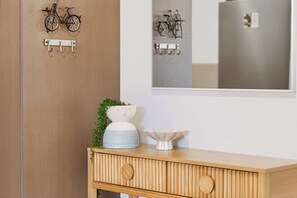 Ein Holzschrank mit einem Spiegel darüber, eine kleine Pflanze und eine weiße Schale darauf.