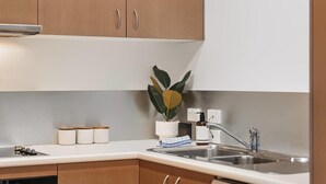 A kitchen with wooden cabinets, a stainless steel sink, and a dish drying rack. - Chic Noosa Pad - Walk to Noosa Hastings St (Noosa)