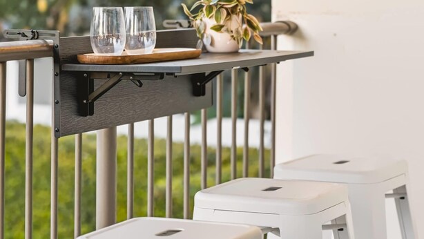 A balcony with a table set for two, featuring two white stools and a small potted plant. - Chic Noosa Pad - Walk to Noosa Hastings St (Noosa)