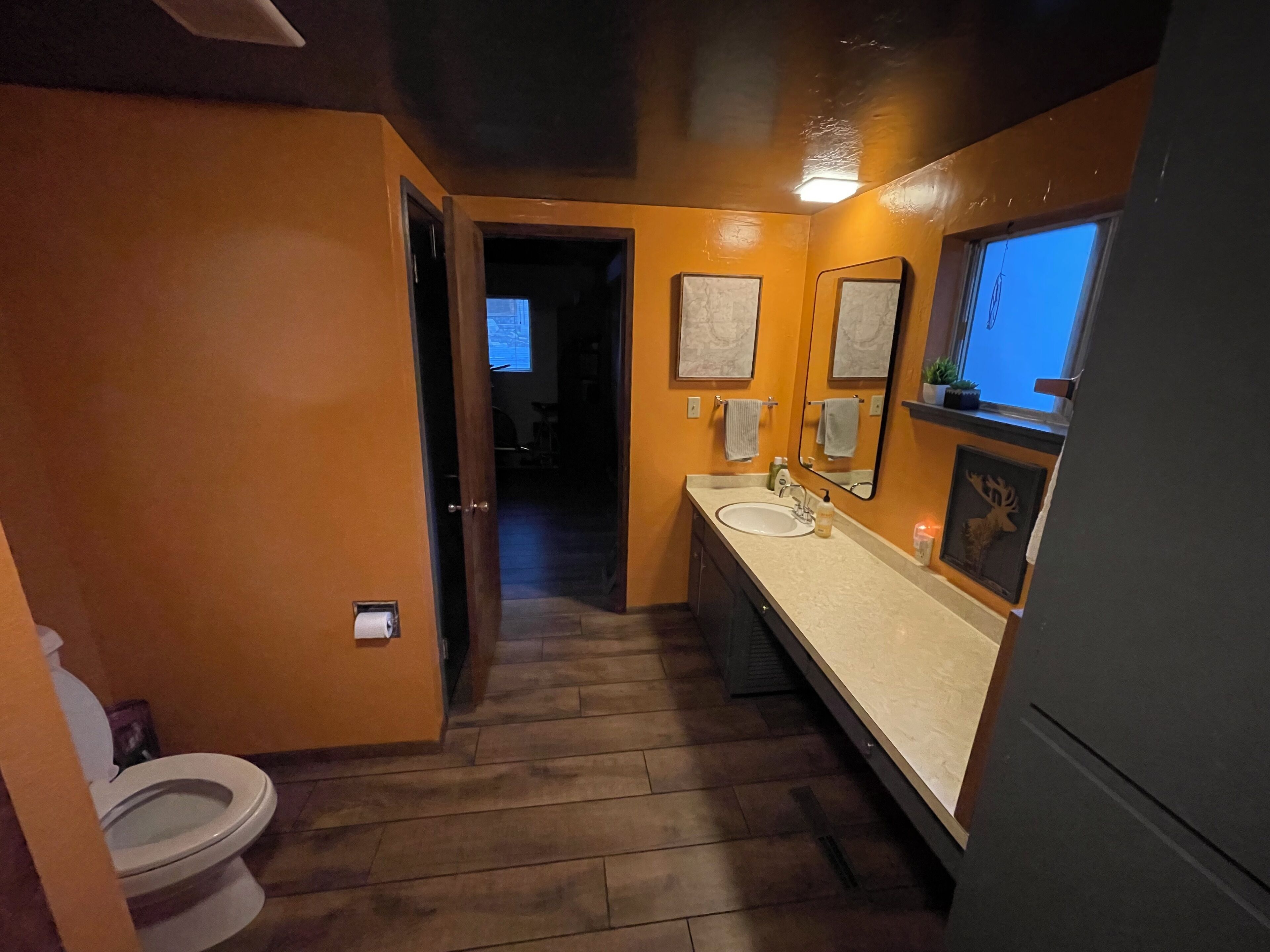 A bathroom with a toilet, sink, and mirror.