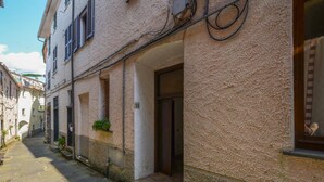 A narrow street with buildings on either side, featuring stone paving, a small entrance with a door, and a potted plant on the wall. - Cozy apartment in Carro with WiFi (Carro)
