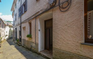 Eine schmale Straße mit Häusern an beiden Seiten, mit Steinpflaster, einem kleinen Eingang mit einer Tür und einem Blumentopf an der Wand.