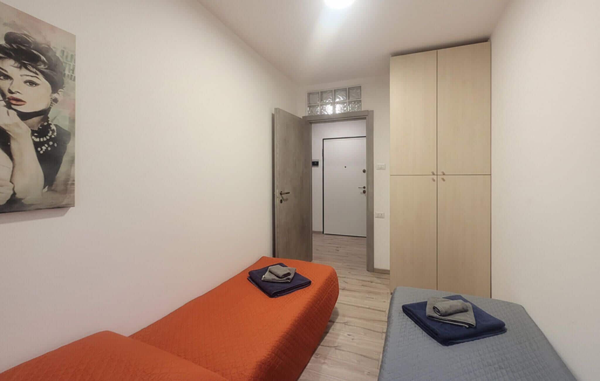A room with two beds, a wardrobe, and a painting on the wall.
