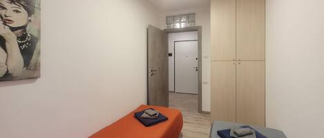 A room with two beds, a wardrobe, and a painting on the wall.