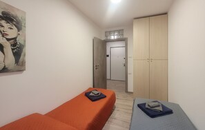 Huoneessa on kaksi sänkyä, vaatekaappi ja seinällä taulu.