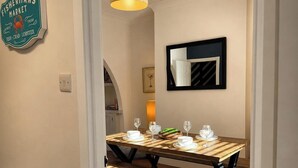 A dining area with a wooden table, benches, and a hanging light fixture. - 3BR Gateshead Home | Free Parking & WiFi (Gateshead)