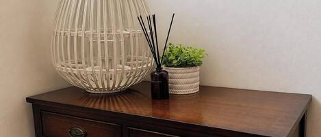 Un bureau en bois avec deux tiroirs et un vase blanc contenant des plantes vertes.