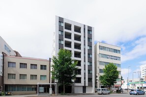 A multi-story building with a modern architectural design, featuring a mix of balconies and windows. - Mondomio 208 (Sapporo)