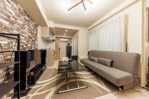 A modern living room with a sofa, a coffee table, and a TV stand. - Mondomio 208 (Sapporo)