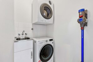 Ein Waschraum mit einer Waschmaschine, einem Trockner und einem Dyson Staubsauger.