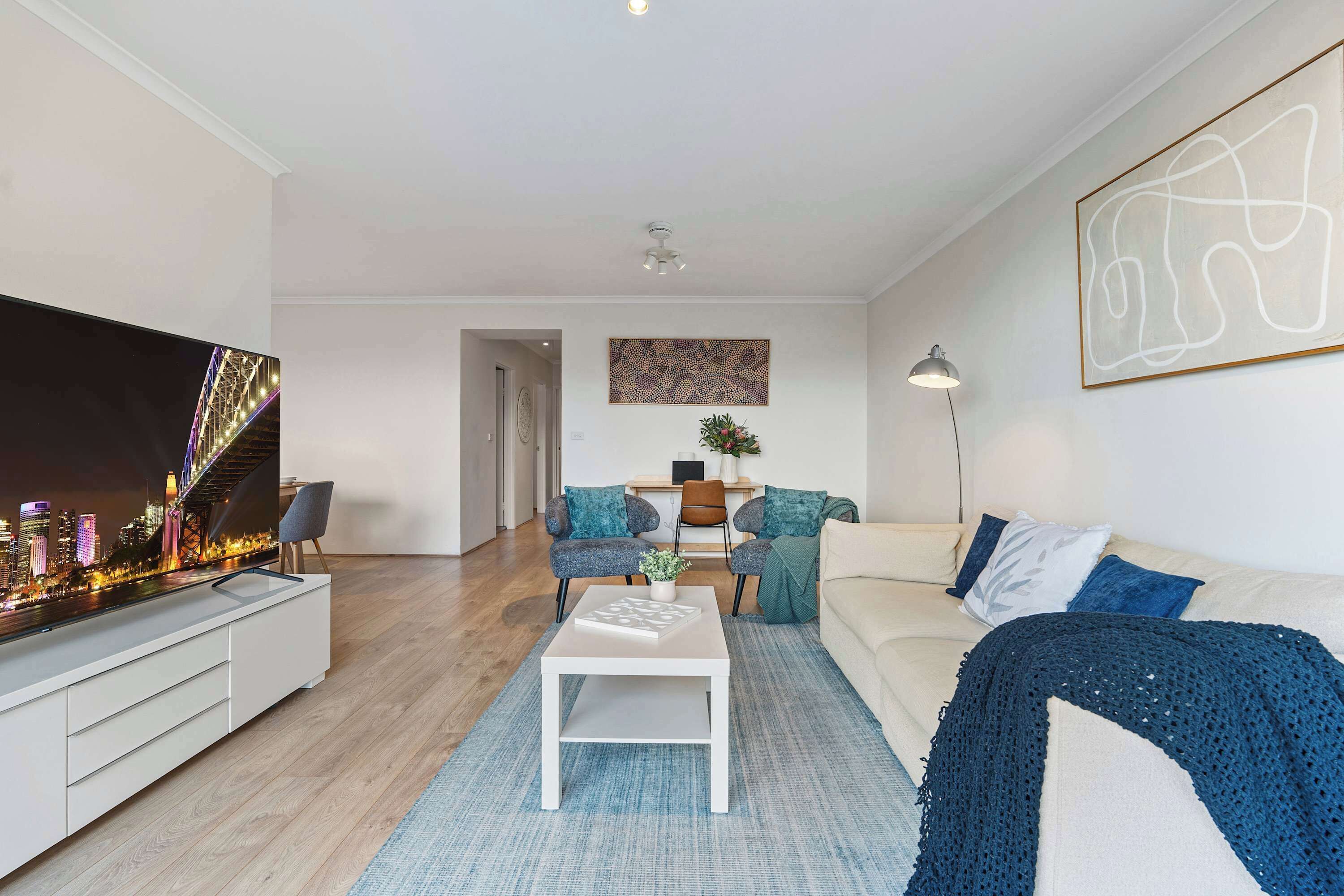 Een moderne woonkamer met een flatscreen televisie, een bank, een salontafel en uitzicht op een stadsbeeld.