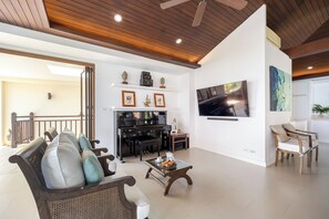 Un salón amplio con un piano, un televisor de pantalla plana y asientos cómodos.