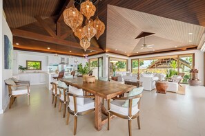 Un salón espacioso con una mesa de comedor de madera, sofás blancos y un ventanal con vistas al exterior.