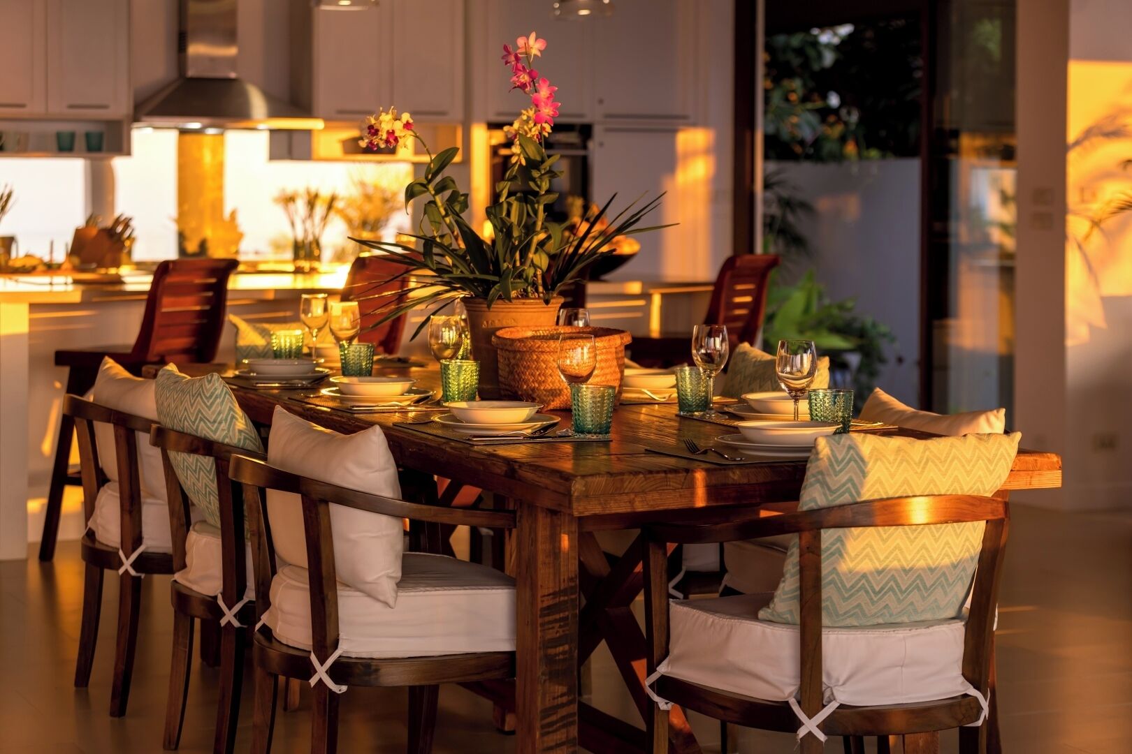 A dining area with a wooden table set for four, surrounded by chairs with white cushions.