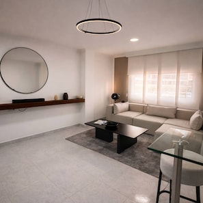 Una sala de estar moderna con un sofá, una mesa de centro y un espejo redondo en la pared.
