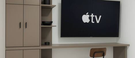 A modern office space with a flat-screen TV mounted on a wall, a desk, and a chair.