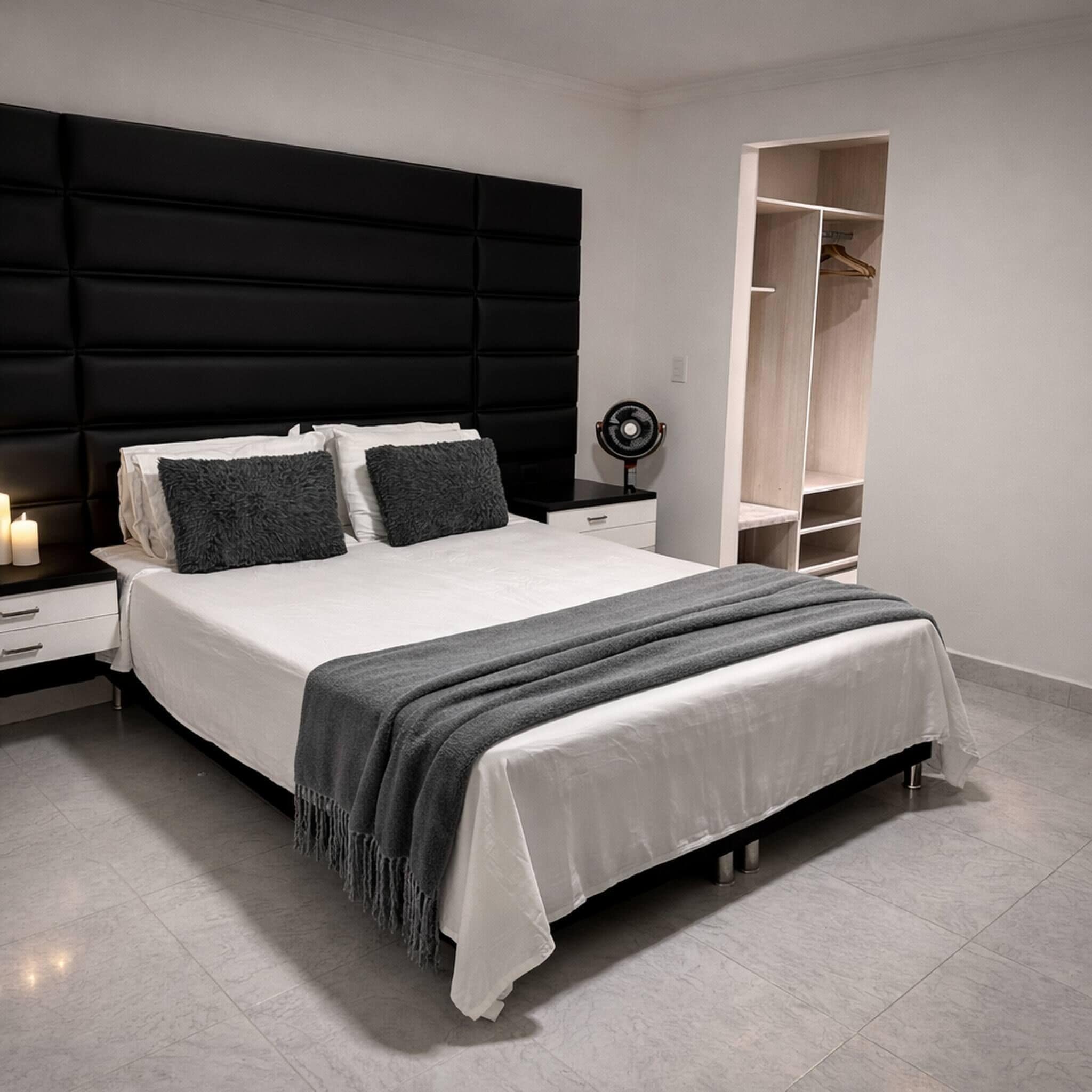 A modern bedroom with a large bed, bedside tables, a wardrobe, and a ceiling fan.