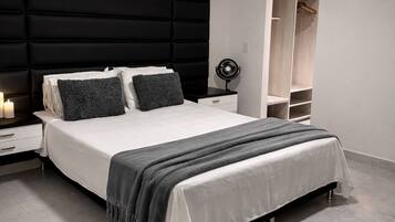 A modern bedroom with a large bed, bedside tables, a wardrobe, and a ceiling fan.