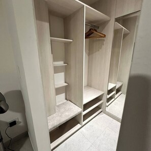Un armario espacioso con varias estanterías y una barra para colgar ropa.