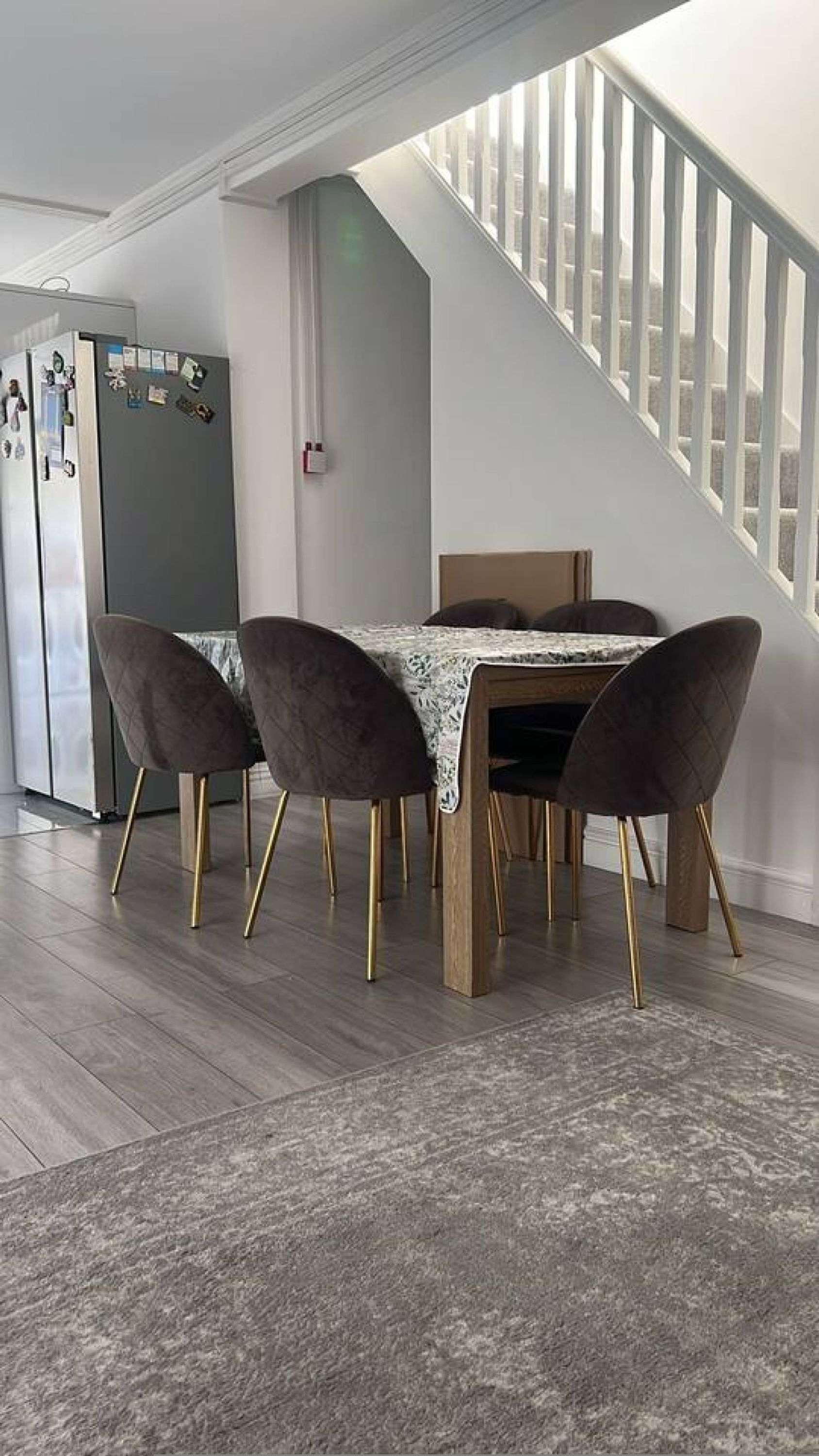 A dining area with a table and chairs, a staircase, and a refrigerator.