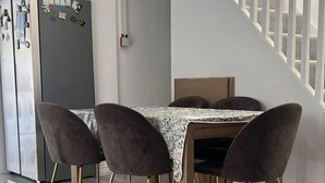 Ein Essbereich mit Tisch und Stühlen, einer Treppe und einem Kühlschrank.